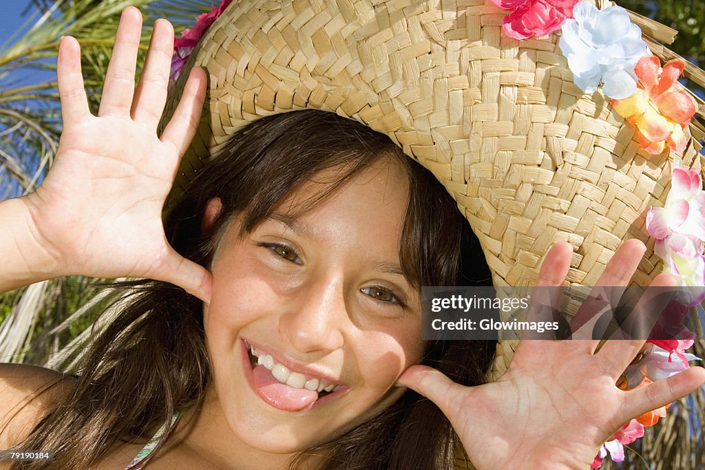 Portrait of a girl wearing a straw hat and sticking her tongue out