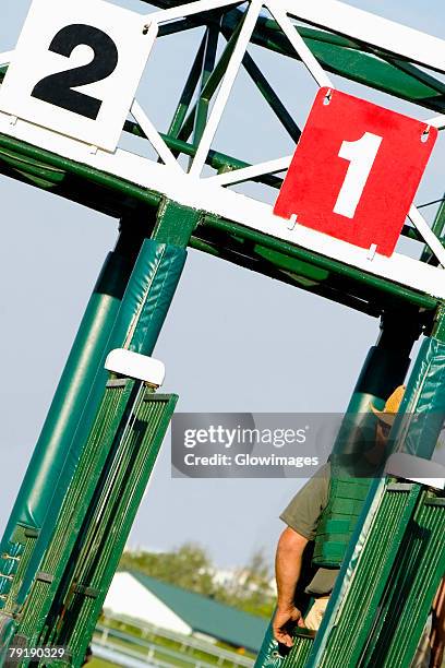 two jockeys at the starting gates on a horseracing track - horse racing starting gate stock pictures, royalty-free photos & images