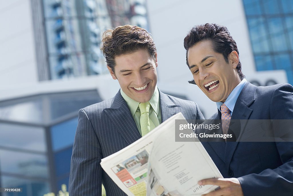 Two businessmen reading a magazine and smiling