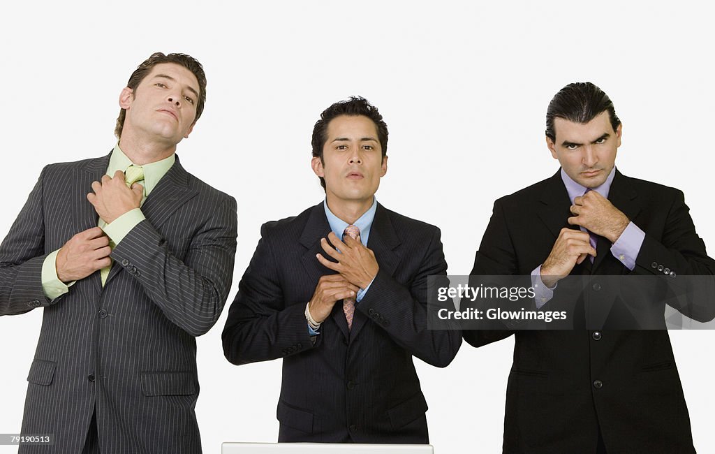 Portrait of three businessmen adjusting their ties
