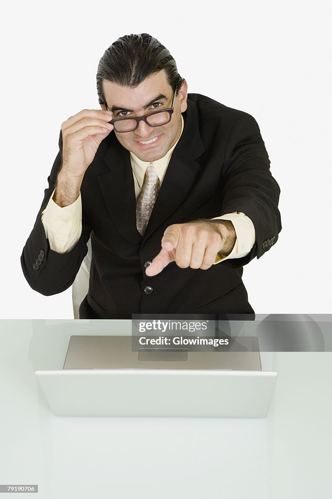 Portrait of a businessman adjusting his eyeglasses and pointing forward