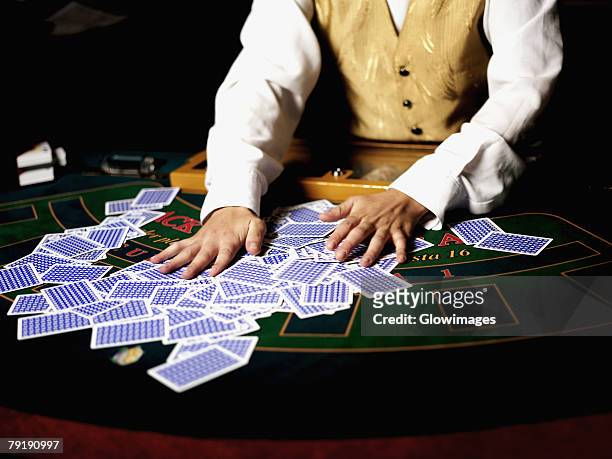mid section view of a casino worker shuffling playing cards on a gambling table - black jack hand stock-fotos und bilder