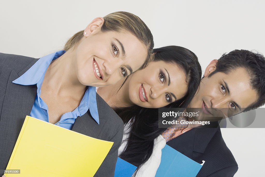 Portrait of a businessman and two businesswomen smiling and holding files