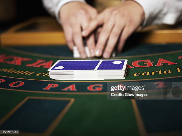 close-up of a casino worker's hand shuffling playing cards on a gambling table - casino worker stock pictures, royalty-free photos & images