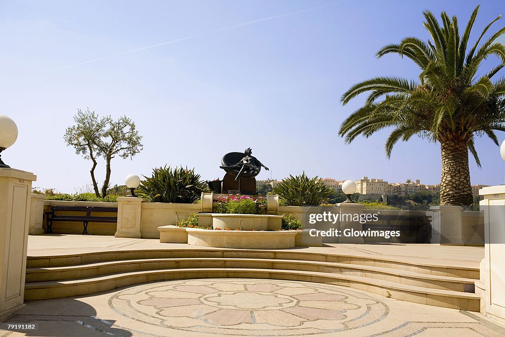 Palm tree and a statue in a garden, Monte Carlo, Monaco