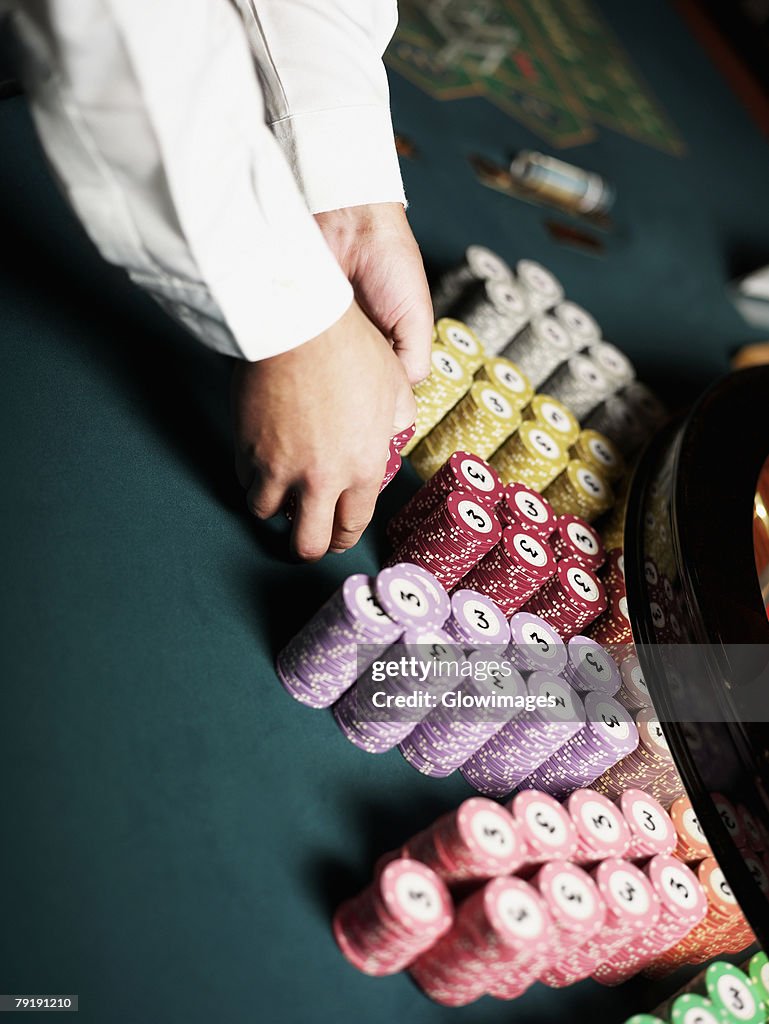 Close-up of a casino worker's hand arranging gambling chips on a gambling table