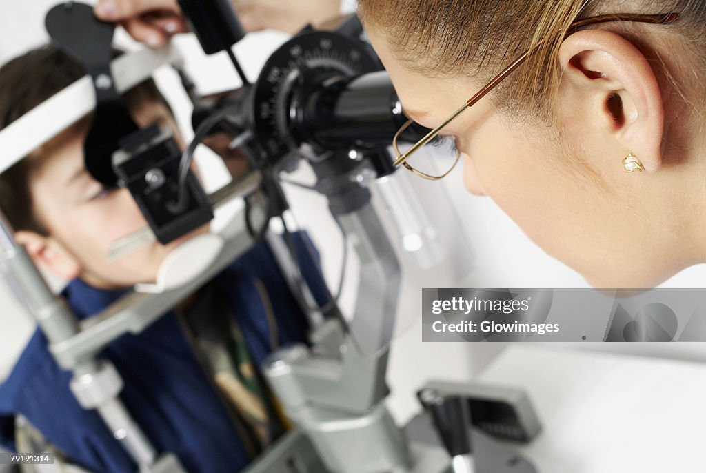 Close-up of a female optometrist examining eyes of a boy