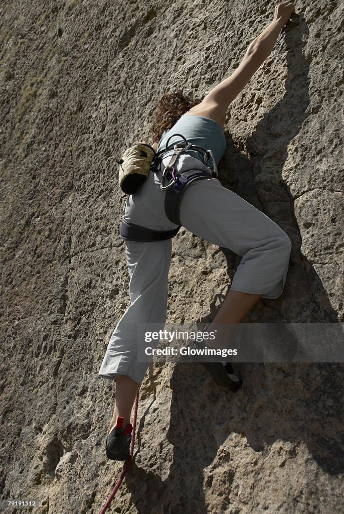 Low angle view of a female rock climber scaling a rock face