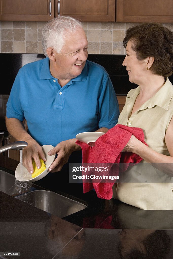 Close-up of a senior couple cleaning plates in the kitchen