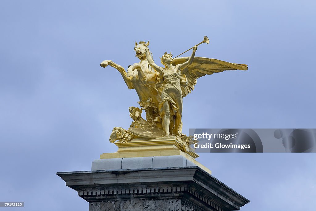 Low angle view of a gilded statue, La Renommee Au Combat, Pont Alexandre III, Paris, France