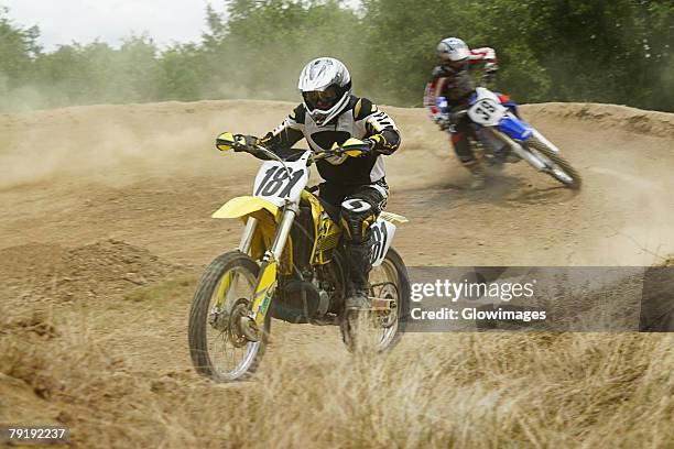 two motocross riders riding motorcycles on a dirt road - motorradsport stock-fotos und bilder