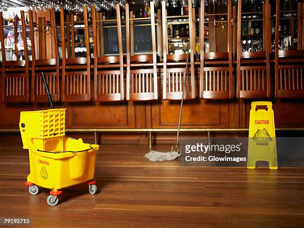 mop and a warning sign in front of a bar counter - daily bucket stockfoto's en -beelden