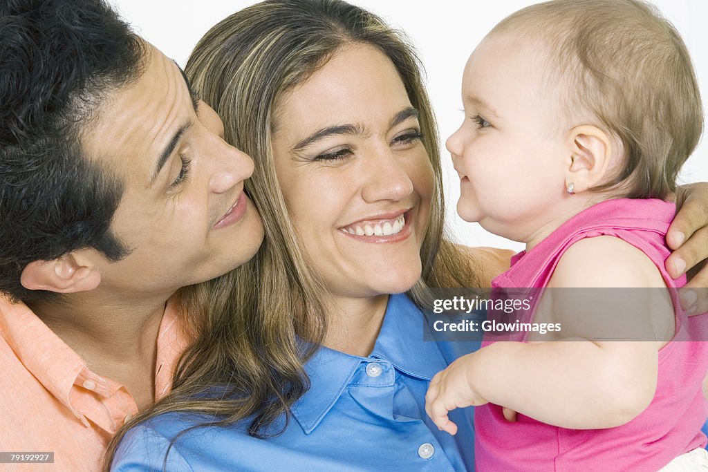 Close-up of a young couple with their daughter smiling