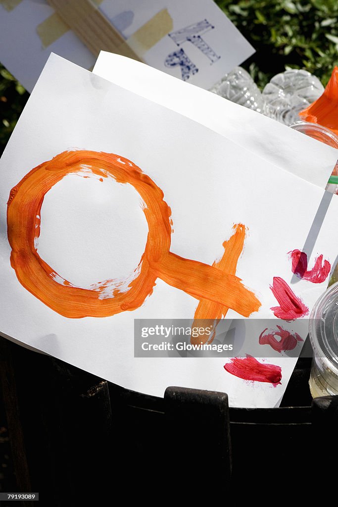 Female symbol and disposable cups in a garbage bin