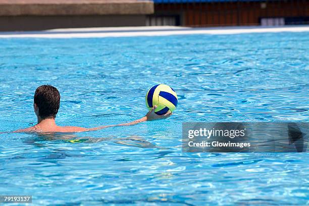 rear view of a man playing water polo in a swimming pool - male throwing water polo ball stockfoto's en -beelden