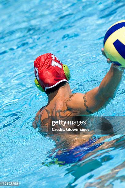 rear view of a mid adult man playing water polo in a swimming pool - male throwing water polo ball stockfoto's en -beelden