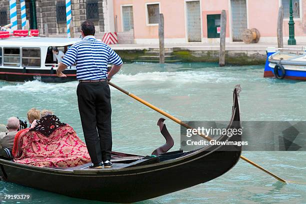 man standing on a gondola in a canal, grand canal, venice, italy - gondolier stock pictures, royalty-free photos & images