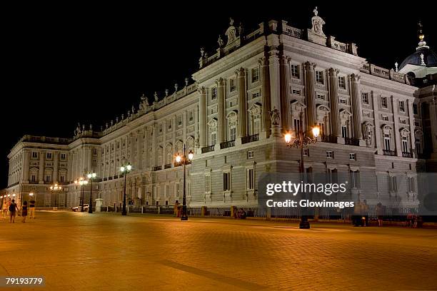 lampposts lit up in front of a palace lit up at night, madrid royal palace, madrid, spain - palacio real de madrid fotografías e imágenes de stock