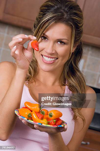 portrait of a young woman showing a red chili pepper - chili woman ストックフォトと画像