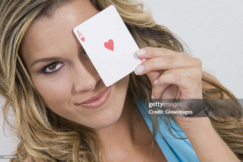 Portrait of a young woman holding an ace card and smiling