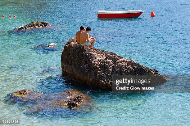 tourists sitting on a rock, capri, campania, italy - capri stock pictures, royalty-free photos & images