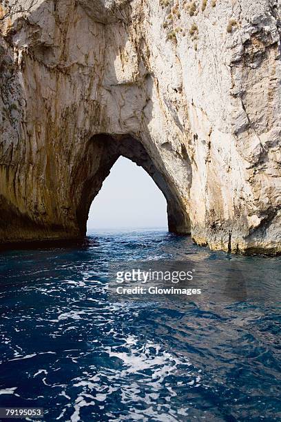 natural arch in a rock formation, faraglioni rocks, capri, campania, italy - faraglioni imagens e fotografias de stock