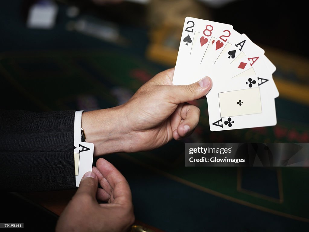 Close-up of a person's hand holding playing cards and hiding an ace in his cuff