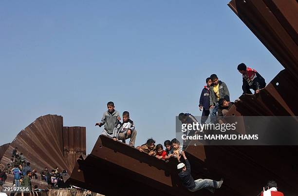 Palestinian children play on the bombed metal fence that used to separte the Gaza Strip from Egypt in the border town of Rafah, 24 January 2008. An...