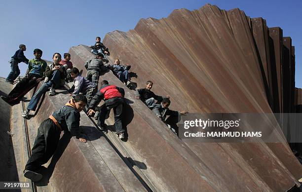 Palestinian children play on the bombed metal fence that used to separte the Gaza Strip from Egypt in the border town of Rafah, 24 January 2008. An...