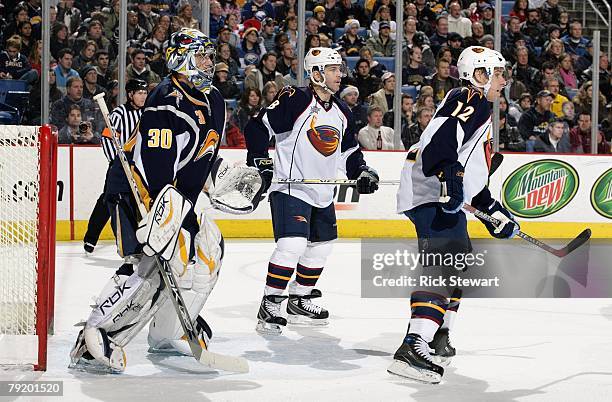 Goaltender Ryan Miller of the Buffalo Sabres defends his net as Todd White and Mark Recchi of the Atlanta Thrashers stand near the crease area during...