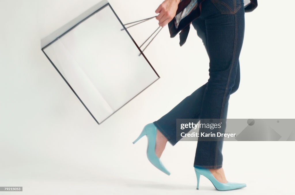 Studio shot of woman walking with shopping bag