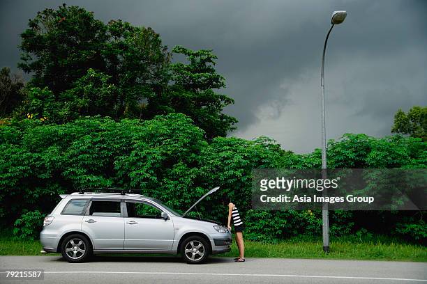 a woman checks under the hood of her car - short skirts in cars stock-fotos und bilder