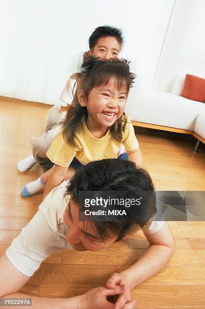 two children sitting on their father's back - lying on back girl on the sofa stock-fotos und bilder