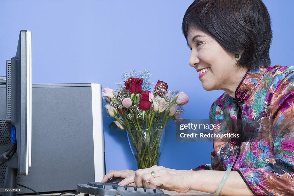 Side profile of a senior woman using a computer and smiling