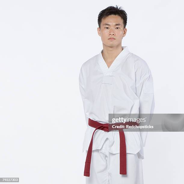 portrait of a young man standing with his hands behind his back - red belt ストックフォトと画像