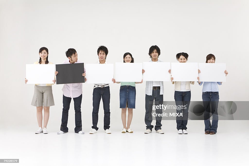 Young people standing with blank message board