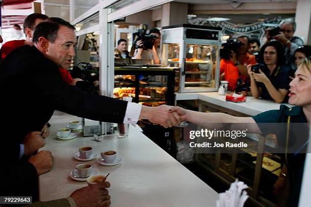 Republican presidential hopeful former Arkansas Gov. Mike Huckabee shakes hands with a waitress after drinking a cup of Cuban espresso with local...