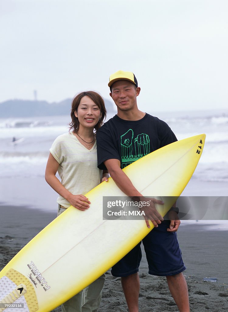 Young couple holding a surf board