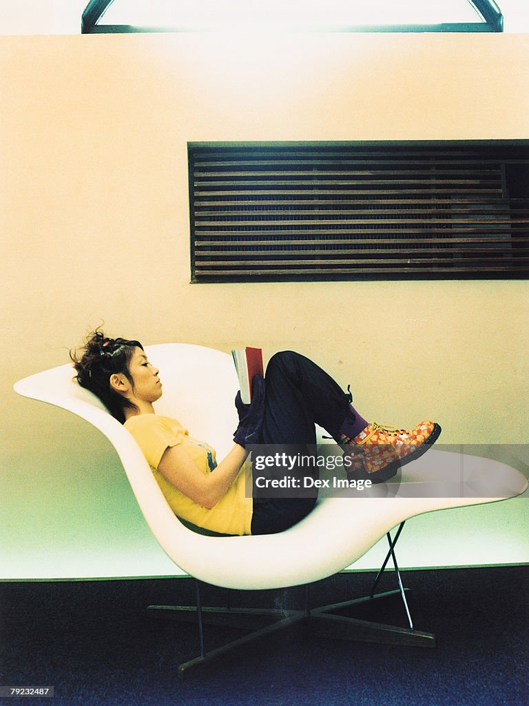 Woman reading book on curved chair