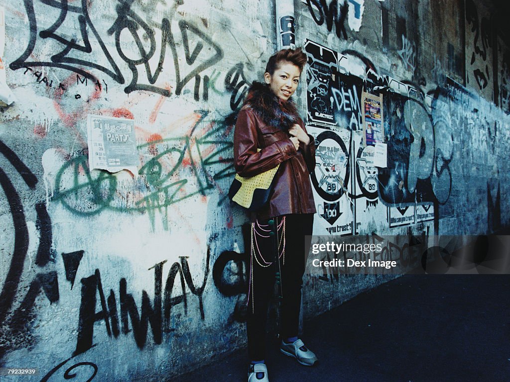 Young woman standing by vandalized wall