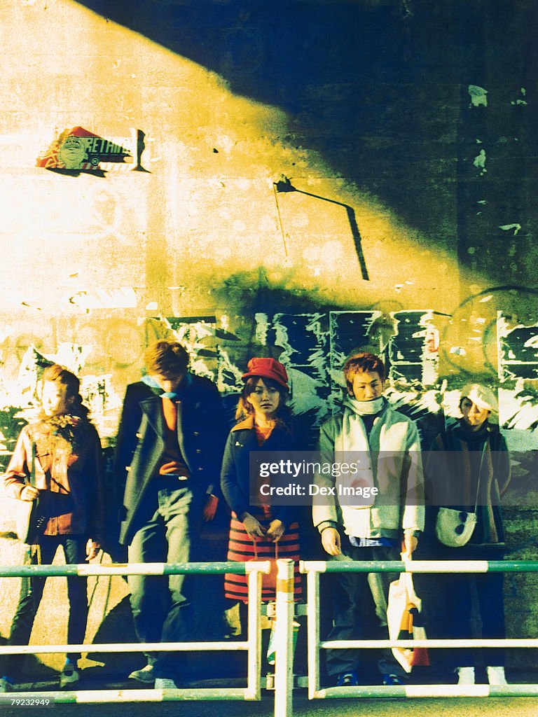 Group of people leaning against vandalized wall