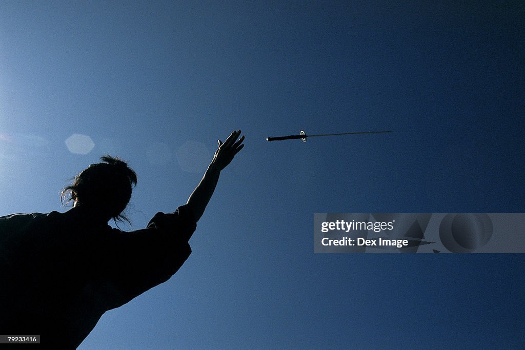 Samurai warrior throws a sword in the air