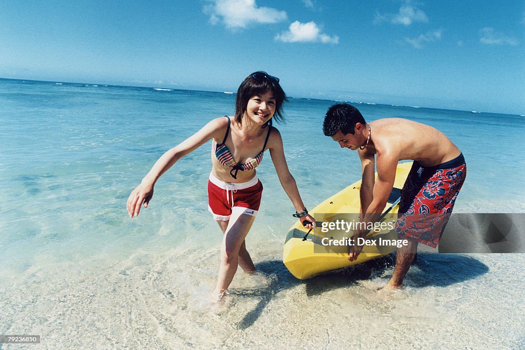 Young couple pulling kayak to shore