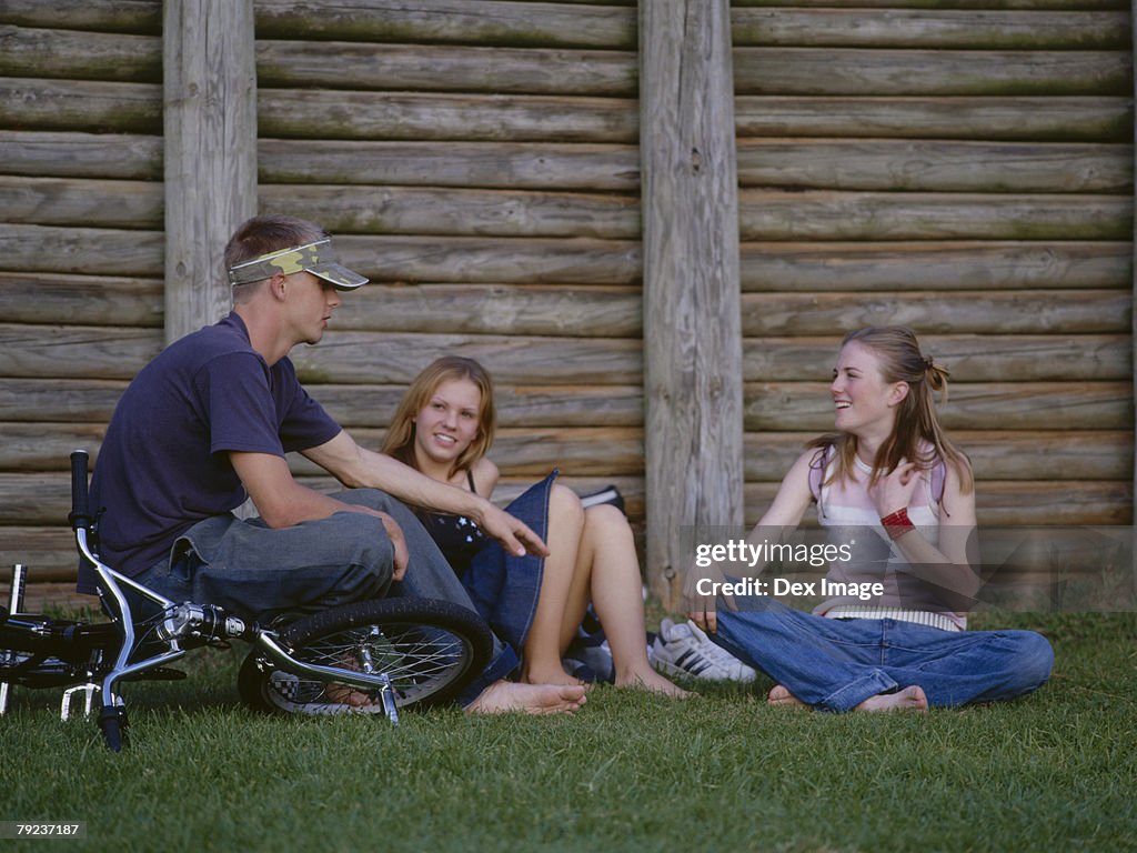 Teenagers sitting together on grass talking