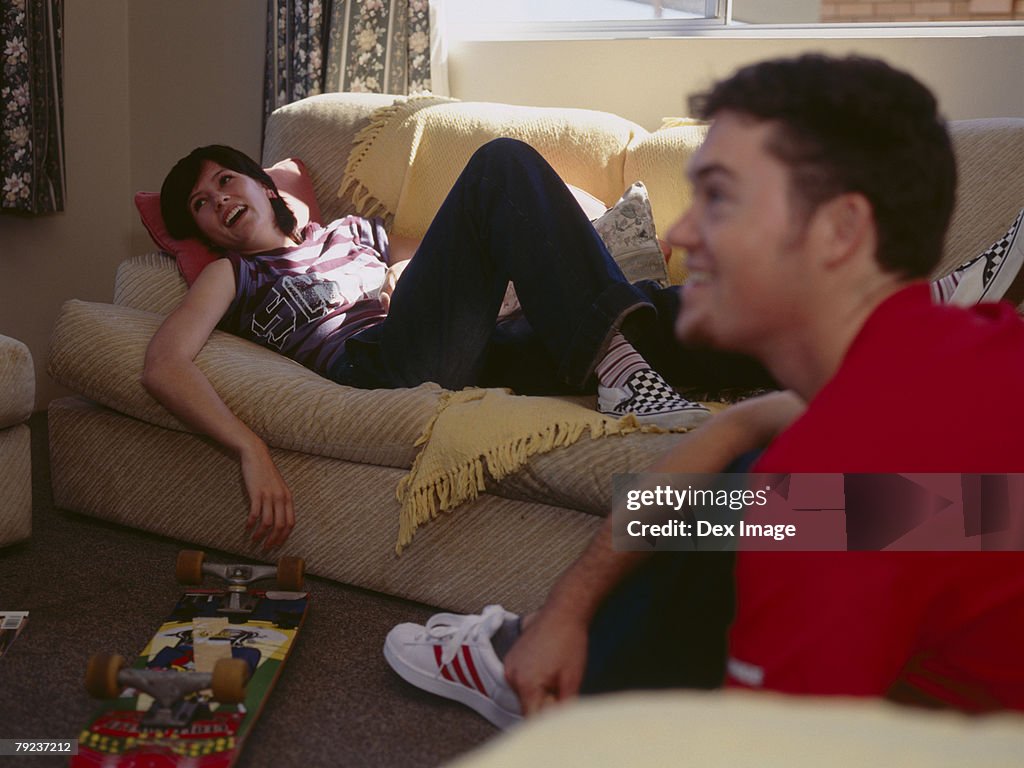 Young woman lying on sofa, while friend on sofa