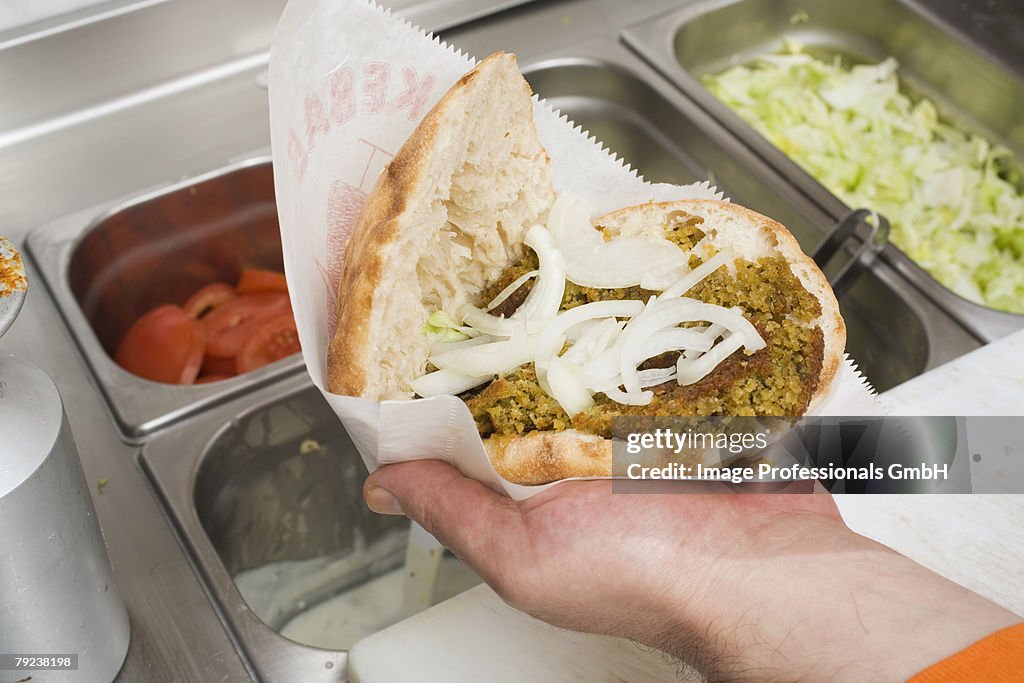 Hand holding opened d?ner kebab with onions