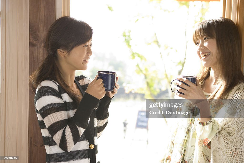 Two girls having coffee, by the window