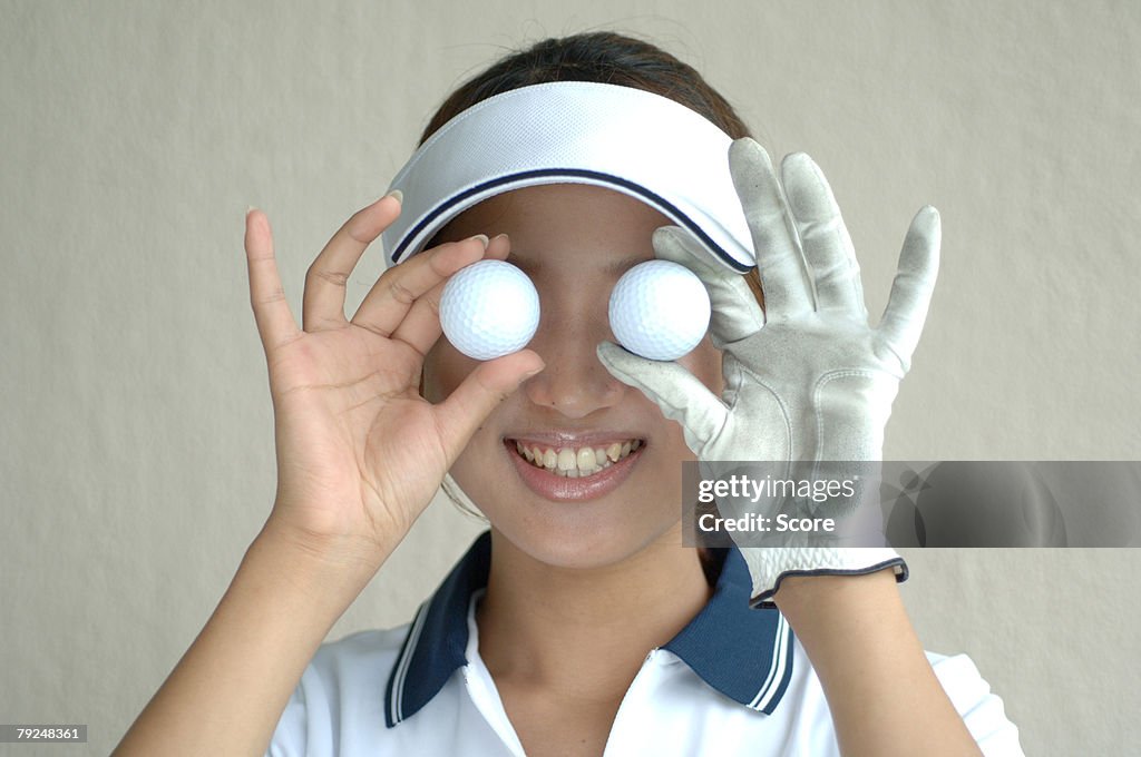 Close up of a woman holding two golf balls in front of her eyes