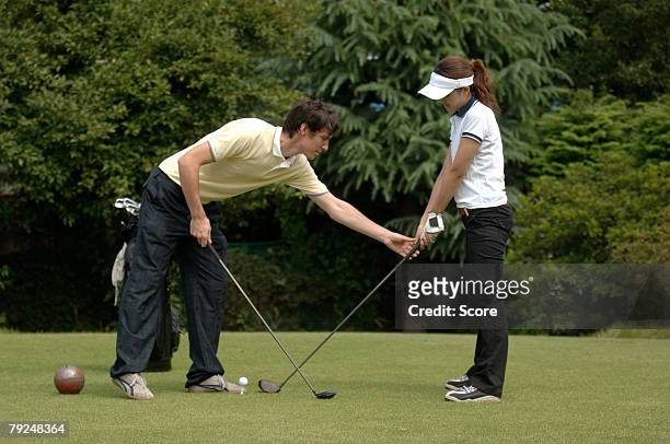 man teaching a woman to play golf - golf driver stock pictures, royalty-free photos & images