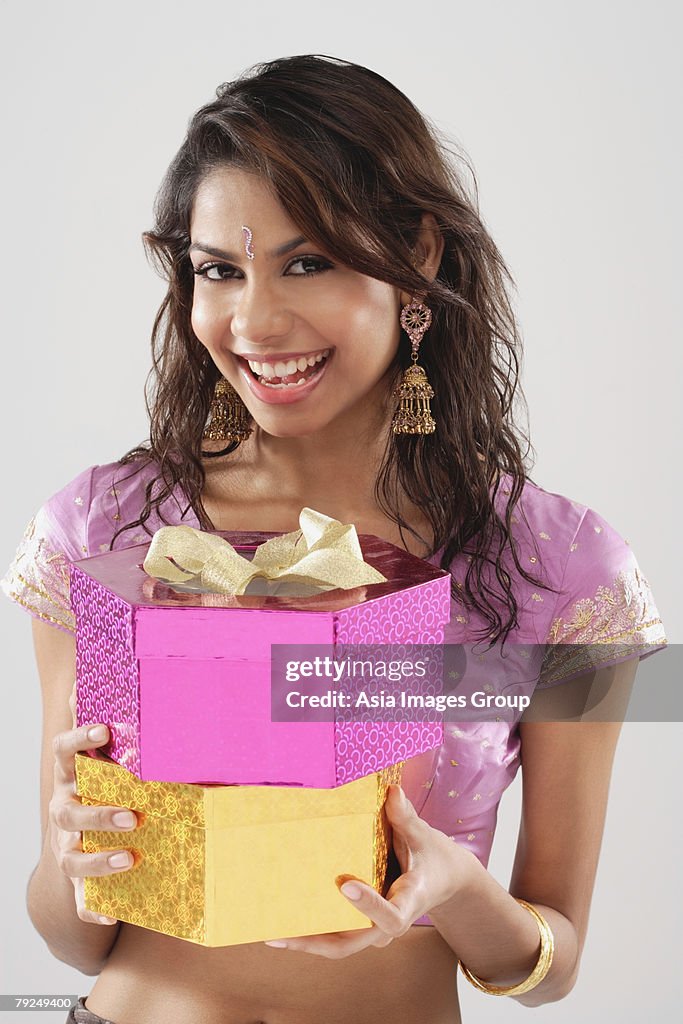 A young woman smiles at the camera as she holds gifts